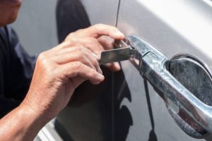 Hand of specialist automotive locksmith repairing car door in Austin, TX.