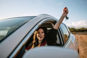 Young woman happily showing car keys through car window after replacement by Austin Locksmith.